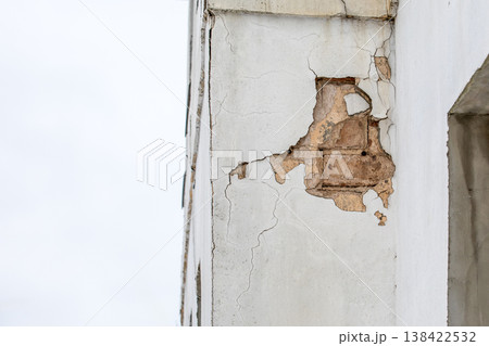 Damaged Building Facade With Cracked Plaster And Exposed Masonry Section 138422532