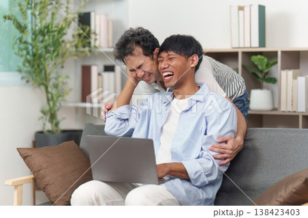 LGBTQ couple laughing together while using a laptop LGBTQ couple laughing together while using a laptop 138423403
