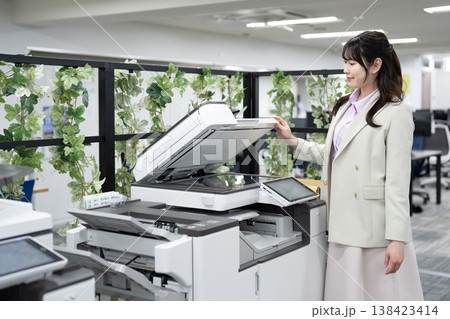 オフィスで複合機を操作する女性社員 138423414