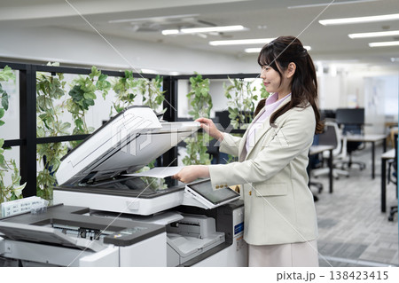 オフィスで複合機を操作する女性社員 138423415