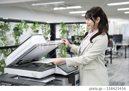 オフィスで複合機を操作する女性社員 138423416