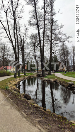 Sunny city park with a bare trees and a deep pond in early spring. Ideal for travel imagery, recreation visuals, and design projects. 138423747