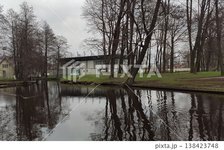 Sunny city park with a bare trees and a deep pond in early spring. Ideal for travel imagery, recreation visuals, and design projects. 138423748