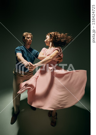 Couple dancing lindy hop with expressive pose and flowing dress studio lighting Couple dancing lindy hop with expressive pose and flowing dress studio lighting 138424725