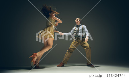 Young couple dancing lindy hop holding hands in dynamic jump studio shot retro style Young couple dancing lindy hop holding hands in dynamic jump studio shot retro style 138424744