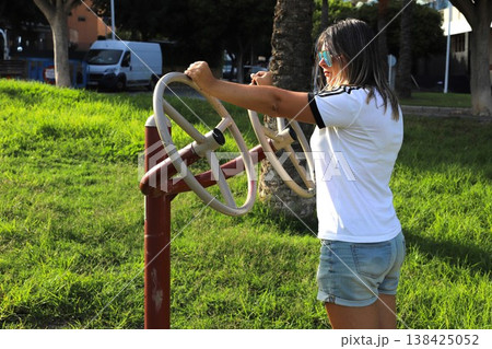 Woman working out in park with hand wheel fitness machine, enhancing upper body strength 138425052