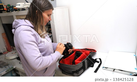 Woman organizing camera gear in a bag at home during the afternoon hours Woman organizing camera gear in a bag at home during the afternoon hours 138425128