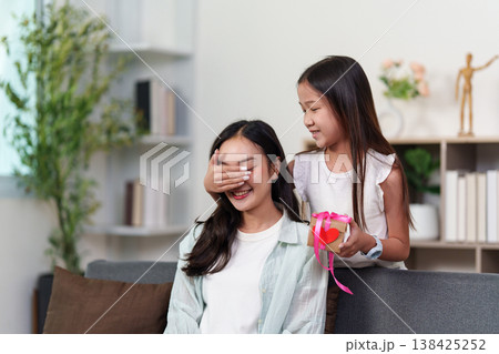 Daughter surprising mother with a gift on Mother's Day Daughter surprising mother with a gift on Mother's Day 138425252