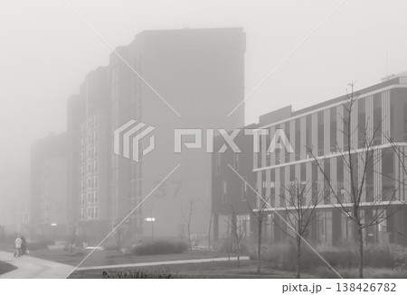Tall modern building rising through fog in an urban city landscape. Moody architectural scene with 138426782