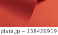 Sweeping coral red paper surface forms a warm flowing background. Smooth matte material shows gentle 138426919