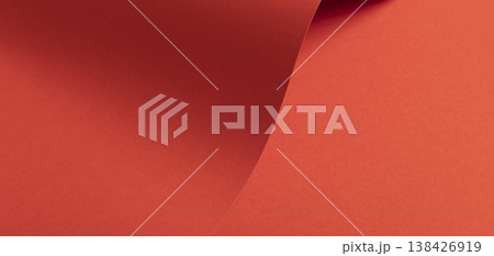 Sweeping coral red paper surface forms a warm flowing background. Smooth matte material shows gentle 138426919