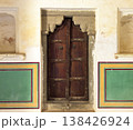 Traditional carved wooden door set within an old plastered wall decorated with colorful geometric 138426924