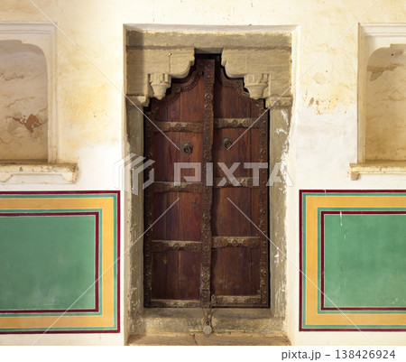 Traditional carved wooden door set within an old plastered wall decorated with colorful geometric Traditional carved wooden door set within an old plastered wall decorated with colorful geometric 138426924