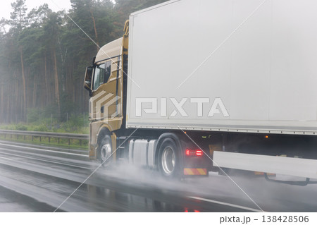 Close-up semi-trailer truck wheel driving fast Splashing Water on Highway, Risk of Aquaplaning on Wet Road. Detail view of hydroplane danger on rainy asphalt surface. Bad dangerous weather conditions Close-up semi-trailer truck wheel driving fast Splashing Water on Highway, Risk of Aquaplaning on Wet Road. Detail view of hydroplane danger on rainy asphalt surface. Bad dangerous weather conditions 138428506