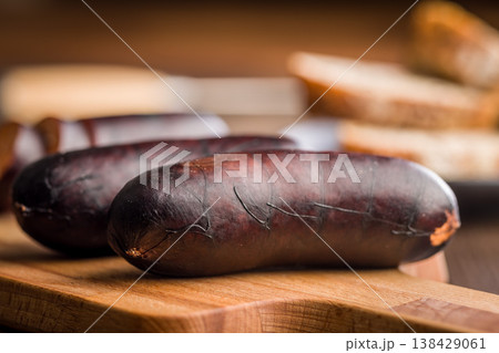 Smoked Blood Sausage (Black Pudding) on Wooden Cutting Board With Bread in Background Smoked Blood Sausage (Black Pudding) on Wooden Cutting Board With Bread in Background 138429061