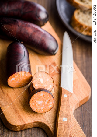 Smoked Sausage Slices On Wooden Cutting Board With Knife And Bread Rustic Kitchen Scene 138429062