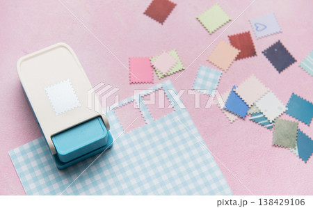 Paper punch creating decorative elements from colorful paper pieces Paper punch creating decorative elements from colorful paper pieces 138429106
