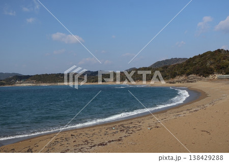 湾の海と波打ち際と砂浜と樹々の山と雲と青空の風景 138429288