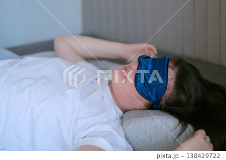 Woman in white pajamas rests with orthopedic pillow and sleep mask, deep restorative sleep and comfort for healthy rest Woman in white pajamas rests with orthopedic pillow and sleep mask, deep restorative sleep and comfort for healthy rest 138429722