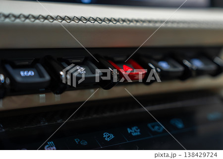 Close up shows stitched leather trim, toggle style switches, and a red hazard button. Glossy touch panel shows icons for parking sensors, A C, and seat controls indoors. Close up shows stitched leather trim, toggle style switches, and a red hazard button. Glossy touch panel shows icons for parking sensors, A C, and seat controls indoors. 138429724