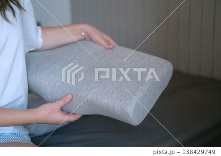 Woman holding orthopedic pillow before sleep showing care for health proper posture and importance of comfort and ergonomic design for quality rest Woman holding orthopedic pillow before sleep showing care for health proper posture and importance of comfort and ergonomic design for quality rest 138429749