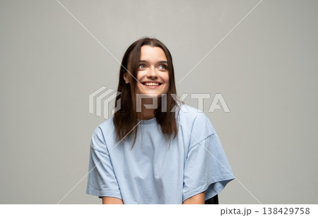 Smiling woman with long brown hair feeling cheerful, looking up and genuinely laughing, expressing joy and positive emotions 138429758