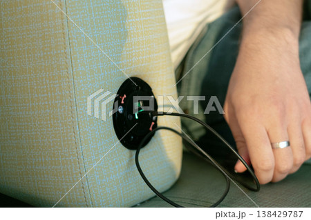 Close up of built in airport seat charger man hand connecting black smartphone to cable modern technology provides comfort and keeps devices powered and connected anywhere Close up of built in airport seat charger man hand connecting black smartphone to cable modern technology provides comfort and keeps devices powered and connected anywhere 138429787