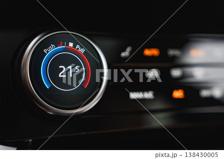 A close up shows a climate control dial at 21.5 C with blue and red arcs, seat and fan icons marked Push and Pull, and orange backlit AUTO and recirculation buttons in low light. 138430005