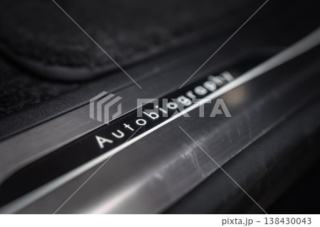 A close up shows a Range Rover Autobiography door sill plate in brushed metal and black, seen in a premium workshop or showroom with soft directional lighting. 138430043