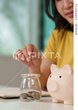 Woman saving money with piggy bank and jar 138430712