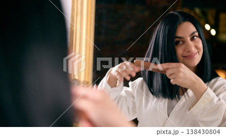 Woman smiling while combing hair during beauty routine Woman smiling while combing hair during beauty routine 138430804