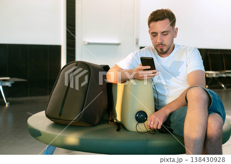 Man working in airport waiting lounge using built in charging stations modern infrastructure enables comfort and staying connected anywhere in the world 138430928