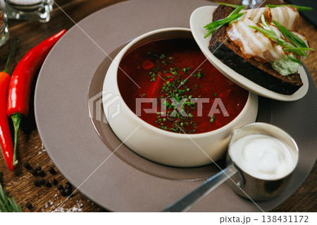 A vibrant Red Soup with fresh Bread and elegant garnish on a rustic Wooden Table A vibrant Red Soup with fresh Bread and elegant garnish on a rustic Wooden Table 138431172