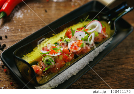 Gourmet tuna tartare with creamy avocado, radish, and salmon roe. Finished with microgreens and presented in a stylish black dish. Exquisite and fresh appetizer in fine dining 138431176