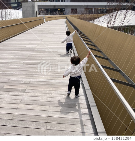 子どもが歩くウッドデッキの通路 兄弟の後ろ姿 都市公園の散歩風景 子どもが歩くウッドデッキの通路 兄弟の後ろ姿 都市公園の散歩風景 138431294