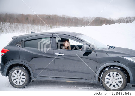 冬の雪の中で車を運転する若い女性 冬の雪の中で車を運転する若い女性 138431645