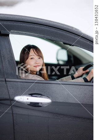 冬の雪の中で車を運転する若い女性 138431652