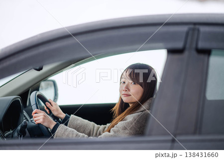 冬の雪の中で車を運転する若い女性 138431660