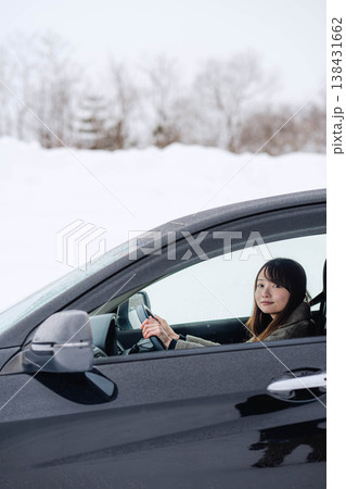 冬の雪の中で車を運転する若い女性 138431662