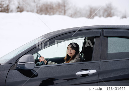 冬の雪の中で車を運転する若い女性 138431663