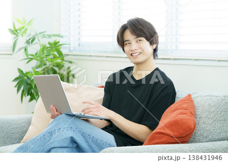 ソファに座ってノートパソコンを操作する若い日本人男性 ソファに座ってノートパソコンを操作する若い日本人男性 138431946