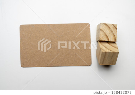 Top-down view of a blank brown kraft paper card and two wooden blocks on a white surface. Ideal for minimalist branding mockups and creative design 138432075