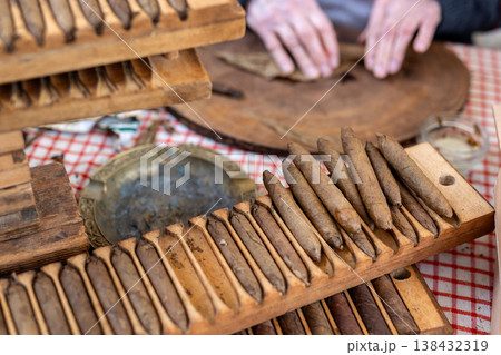 Wooden cigar molds filled rolled tobacco cigars display table during traditional handmade production process. Artisan workshop scene classic tool shape pressing cigars historic tobacco craft industry 138432319