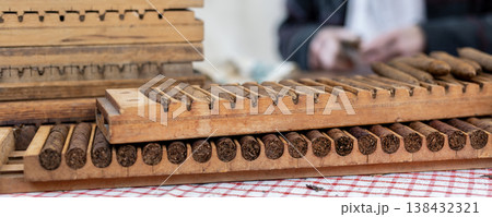 Wooden cigar molds filled rolled tobacco cigars display table during traditional handmade production process. Artisan workshop scene classic tool shape pressing cigars historic tobacco craft industry Wooden cigar molds filled rolled tobacco cigars display table during traditional handmade production process. Artisan workshop scene classic tool shape pressing cigars historic tobacco craft industry 138432321