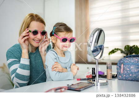 Mother and daughter bonding trying on funny sunglasses indoors 138432886