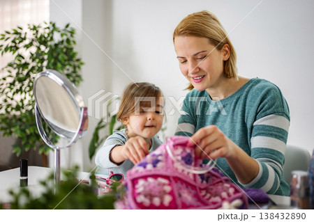Mother and daughter playing with makeup bag together 138432890