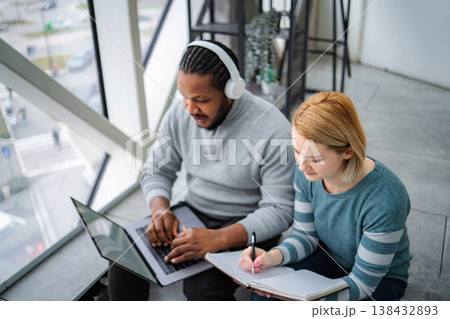 Diverse students collaborating on study project using laptop and notebook Diverse students collaborating on study project using laptop and notebook 138432893