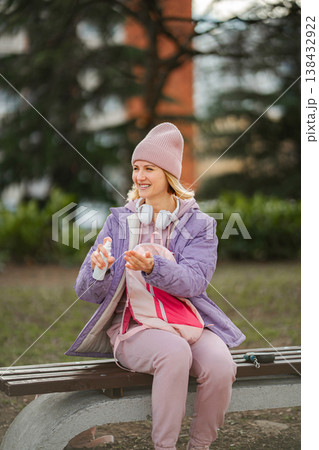 Woman applying hand sanitizer for prevention on park bench 138432922
