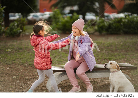 Mother and daughter reuniting in park with dog Mother and daughter reuniting in park with dog 138432925