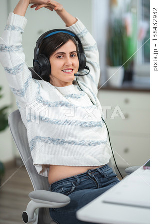 Young woman taking break stretching at home office desk 138432932